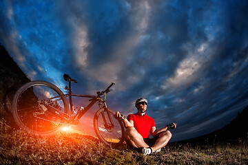 Image showing Man cyclist is engaged in yoga on a sunset