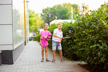 Image showing Two smiling kids, boy and girl running together in town, city in summer day