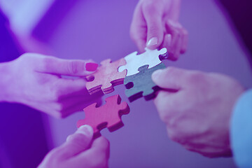 Image showing Group of business people assembling jigsaw puzzle