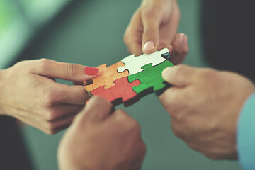 Image showing Group of business people assembling jigsaw puzzle