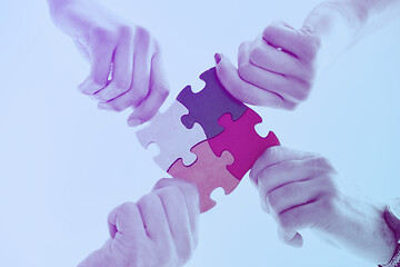 Image showing Group of business people assembling jigsaw puzzle