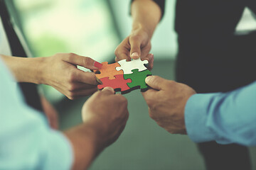 Image showing Group of business people assembling jigsaw puzzle