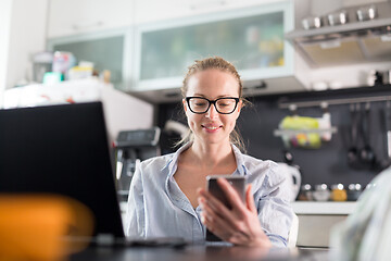 Image showing Stay at home and social distancing. Woman in her casual home clothing working remotly from her kitchen dining table in the morning. Video chatting with friend, family or business clients or partners