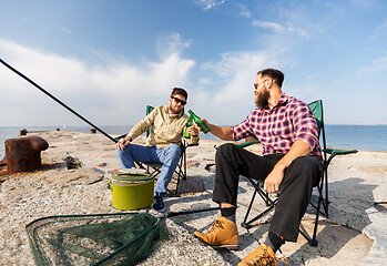 Image showing male friends fishing and drinking beer on sea pier