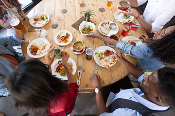 Image showing international friends eating at restaurant