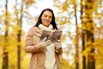 Image showing happy young woman with city guide in autumn park