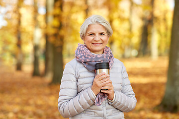 Image showing old woman with hot drink in tumbler at autumn park