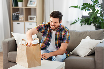 Image showing smiling man unpacking takeaway food at home