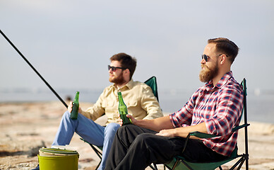 Image showing happy friends fishing and drinking beer on pier