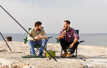 Image showing happy friends fishing and eating sandwiches