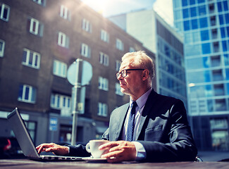 Image showing senior businessman with laptop drinking coffee