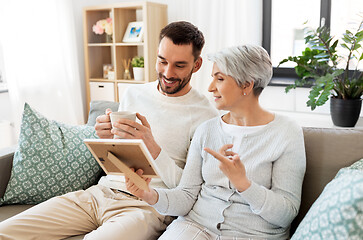 Image showing adult son and senior mother with photo at home