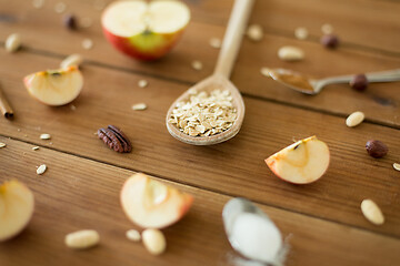 Image showing oatmeal in wooden spoon, cut apples and nuts