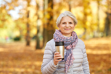 Image showing old woman with hot drink in tumbler at autumn park