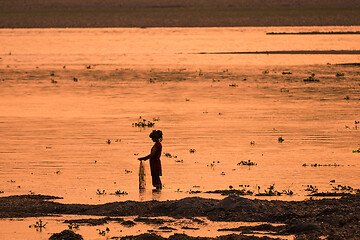 Image showing Asian Woman fishing in the river, silhouette at sunset