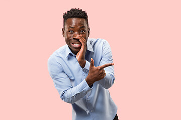 Image showing The young man whispering a secret behind her hand over pink background