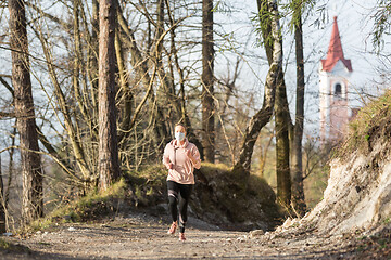 Image showing Corona virus, or Covid-19, is spreading all over the world. Portrait of caucasian sporty woman wearing a medical protection face mask while running in nature.