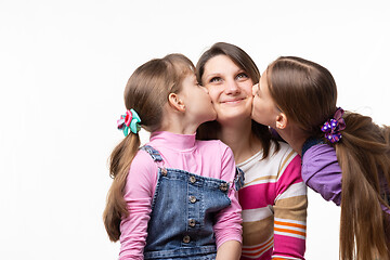 Image showing Two sisters kiss mom on the cheek, mom joyfully looks up