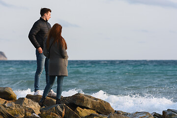 Image showing Two young people standing on a stone beach discussing the current situation.