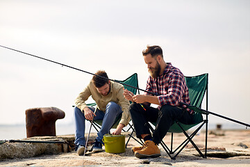 Image showing friends adjusting fishing rods with bait on pier