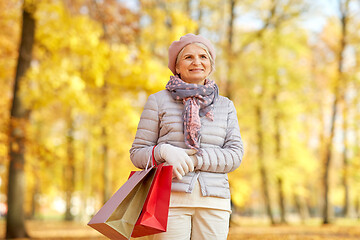 Image showing senior woman with shopping bags at autumn park