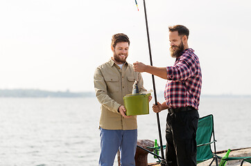 Image showing male friends with fish and fishing rods on pier