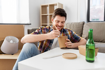 Image showing smiling man eating takeaway food at new home