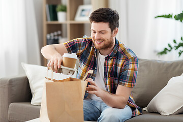 Image showing smiling man unpacking takeaway food at home