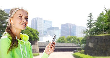 Image showing woman listening to music on smartphone at city