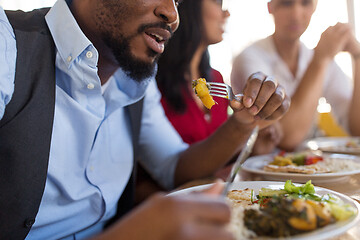 Image showing african man eating with friends at restaurant