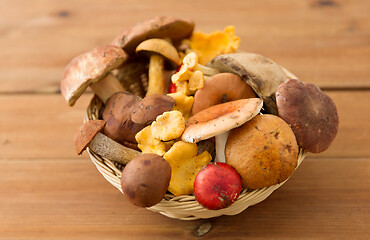 Image showing basket of different edible mushrooms on wood