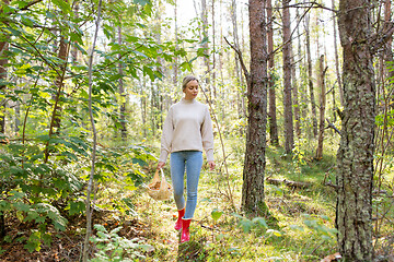 Image showing young woman picking mushrooms in autumn forest