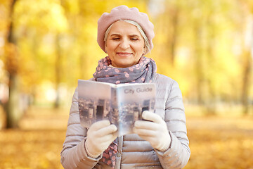 Image showing senior woman with city guide at autumn park