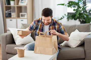 Image showing smiling man unpacking takeaway food at home