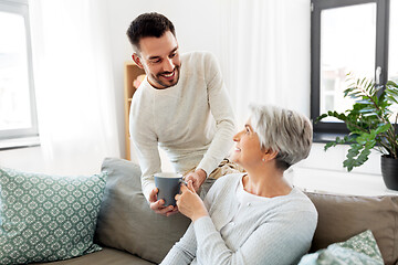 Image showing adult son bringing coffee to senior mother at home