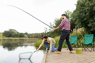 Image showing male friends with net and fishing rods on lake