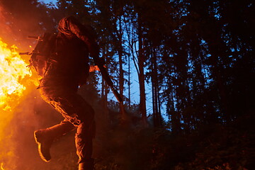 Image showing Soldier in Action at Night jumping over fire