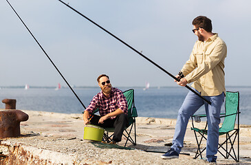 Image showing male friends with fishing rods on sea pier