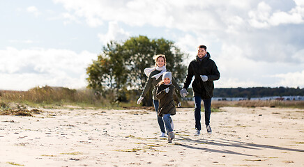 Image showing happy family running along autumn beach