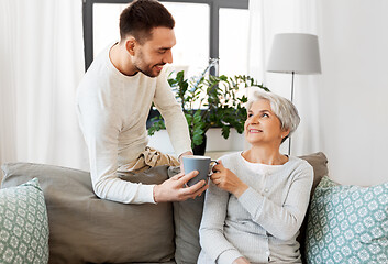 Image showing adult son bringing coffee to senior mother at home