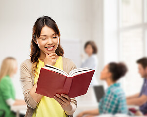 Image showing happy asian woman reading book at school