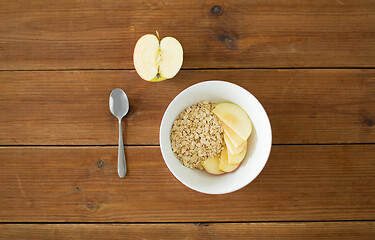 Image showing oatmeal in bowl with apple and spoon on table