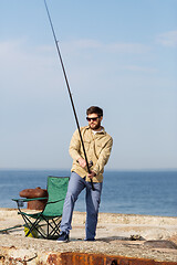 Image showing bearded fisherman with fishing rod on sea pier