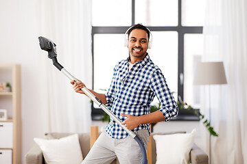 Image showing man in headphones with vacuum cleaner at home