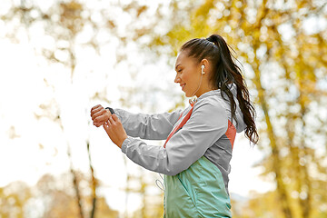 Image showing woman looking at fitness tracker in autumn park