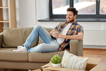 Image showing man with boxes and drinking coffee at new home