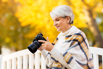 Image showing senior woman with photo camera at autumn park