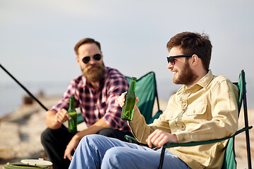 Image showing happy friends fishing and drinking beer on pier