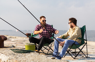 Image showing happy male friends with rods talking about fishing