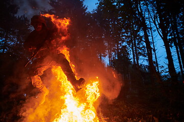 Image showing Soldier in Action at Night jumping over fire